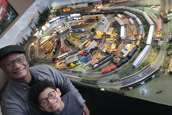 Thomas and his son pose with the family’s model railroad. Thomas and his son pose with the family’s model railroad.